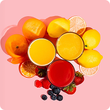 Fruits and juices arranged in a heart shape on a pink background