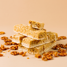 Stack of granola bars with scattered nuts on a beige background